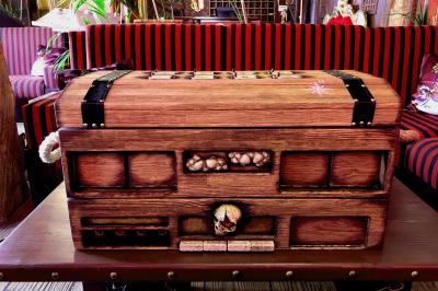 Vue nocturne d'un complexe de loisirs avec piscine illuminée, bâtiments thématiques et paysage urbain en arrière-plan.