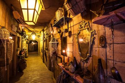 Vue nocturne d'un complexe de loisirs avec piscine illuminée, bâtiments thématiques et paysage urbain en arrière-plan.