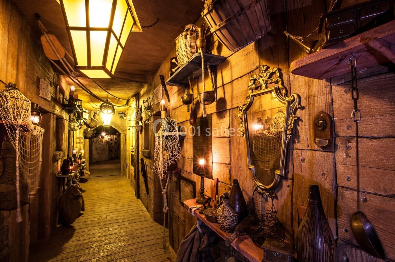 Couloir en bois décoré de lanternes, miroirs, filets et objets anciens, créant une ambiance rustique et chaleureuse.