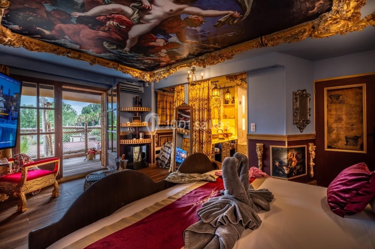 Chambre décorée de manière baroque avec lit, fresque au plafond, mobilier doré et accès à une terrasse extérieure.