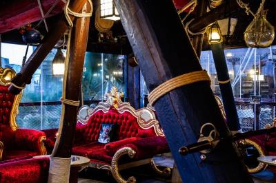 Vue nocturne d'un complexe de loisirs avec piscine illuminée, bâtiments thématiques et paysage urbain en arrière-plan.