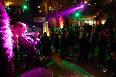Vue nocturne d'un complexe de loisirs avec piscine illuminée, bâtiments thématiques et paysage urbain en arrière-plan.