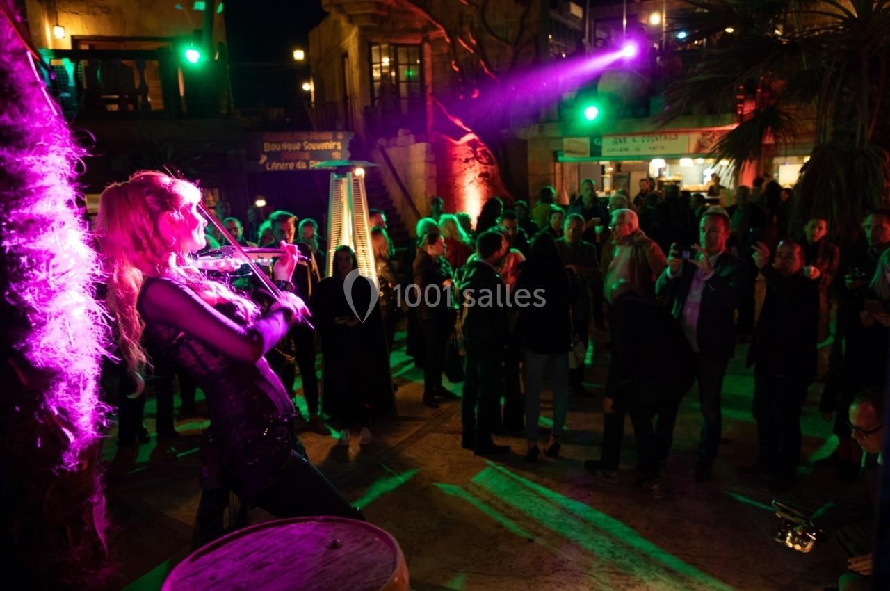 Une violoniste joue sur scène devant un public en soirée, éclairée par des lumières colorées.