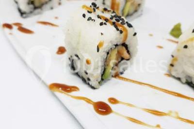 Vue nocturne d'un complexe de loisirs avec piscine illuminée, bâtiments thématiques et paysage urbain en arrière-plan.