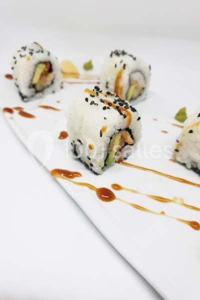 Assortiment de makis garnis d'avocat, saumon et sésame, présentés sur une assiette avec sauce décorative.