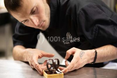 Vue nocturne d'un complexe de loisirs avec piscine illuminée, bâtiments thématiques et paysage urbain en arrière-plan.