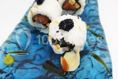 Vue nocturne d'un complexe de loisirs avec piscine illuminée, bâtiments thématiques et paysage urbain en arrière-plan.