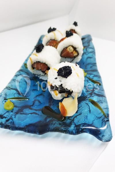 Assortiment de sushis garnis de poisson et de garnitures noires, présentés sur une assiette bleue texturée.