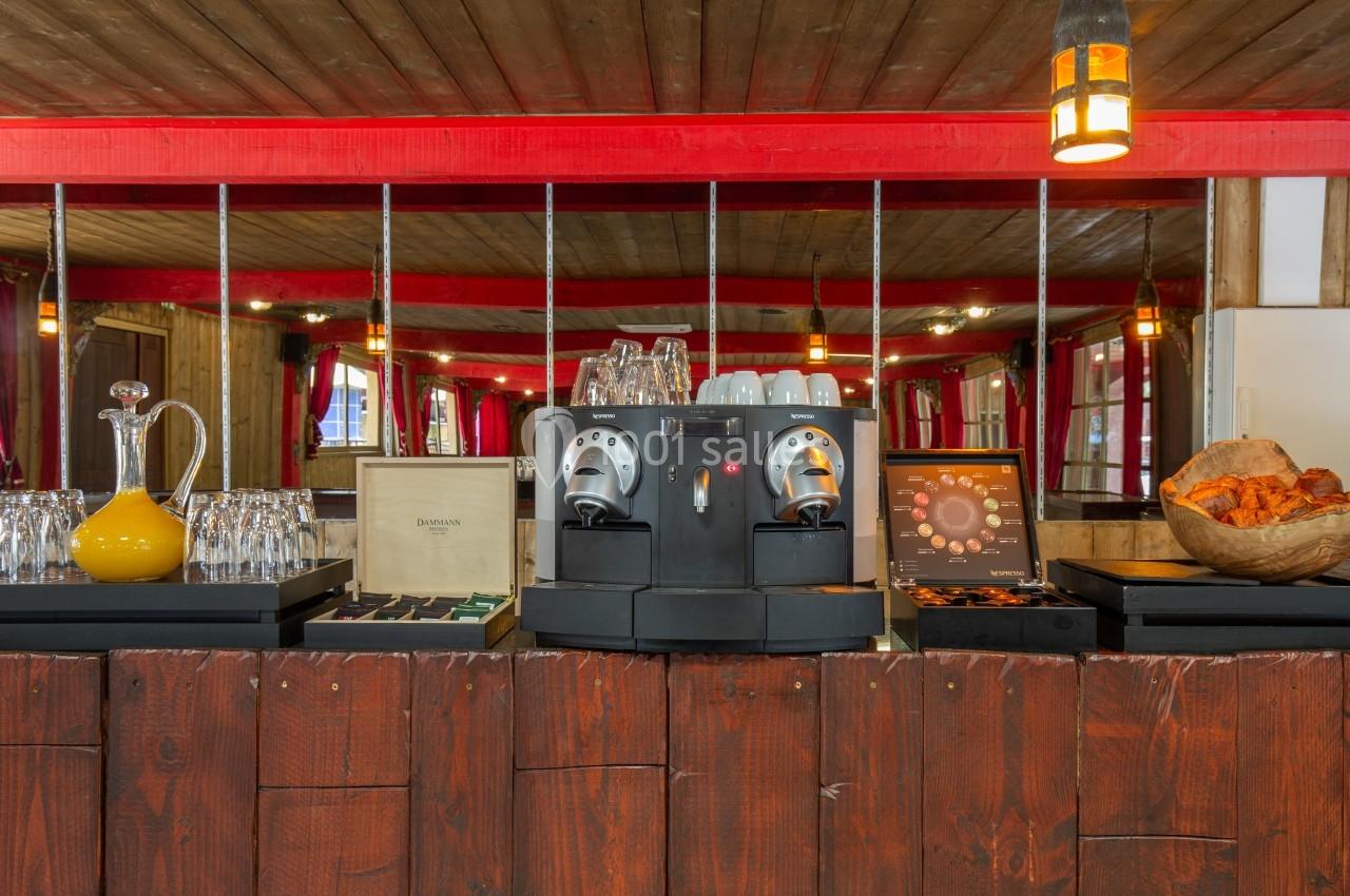 Machine à café avec tasses, carafe, viennoiseries et présentoirs dans un décor en bois avec éclairage chaleureux.
