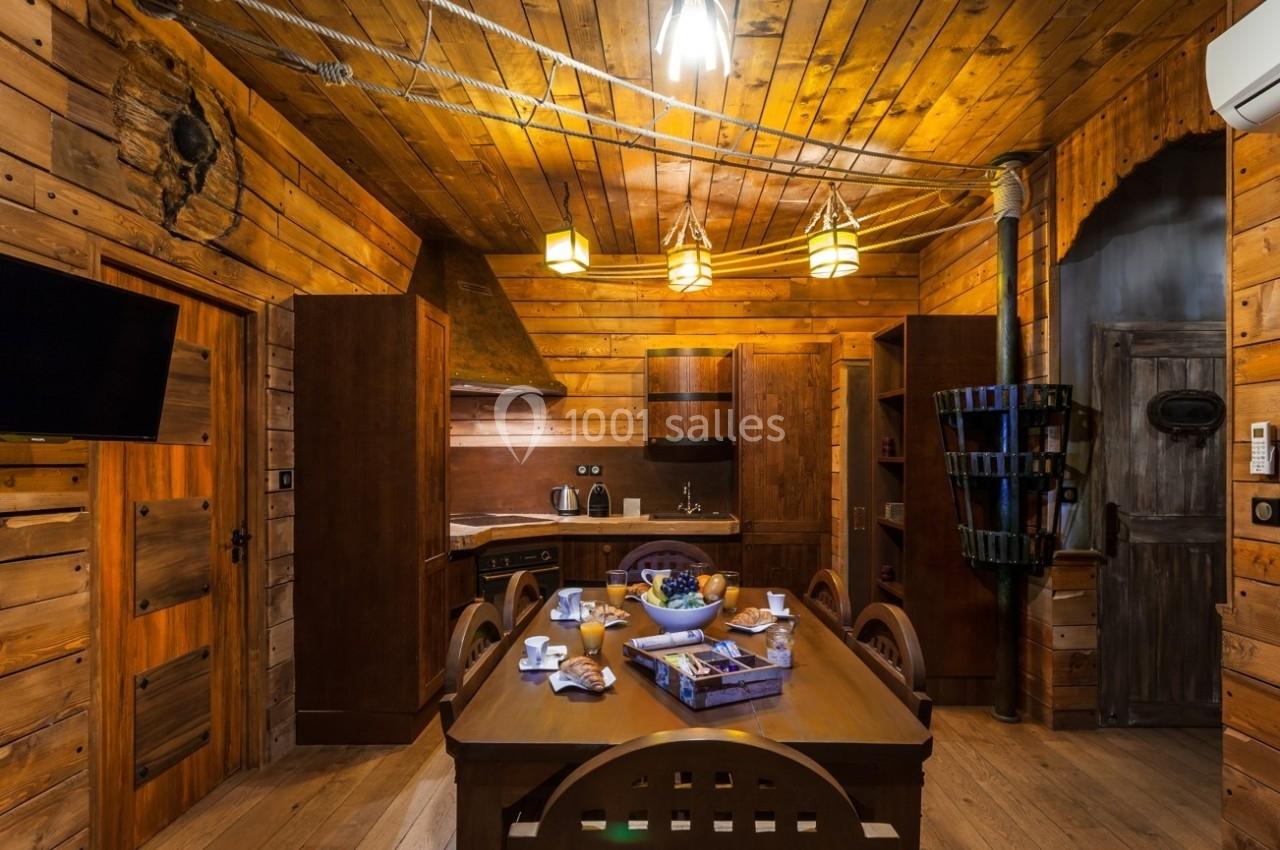 Cuisine en bois rustique avec table dressée, éclairage chaleureux, et éléments décoratifs en bois naturel.