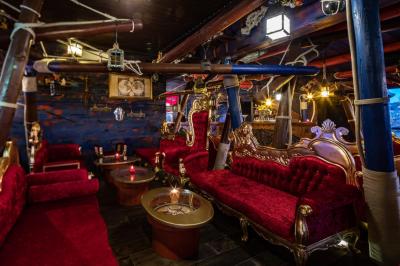 Vue nocturne d'un complexe de loisirs avec piscine illuminée, bâtiments thématiques et paysage urbain en arrière-plan.