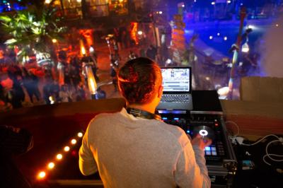 Vue nocturne d'un complexe de loisirs avec piscine illuminée, bâtiments thématiques et paysage urbain en arrière-plan.