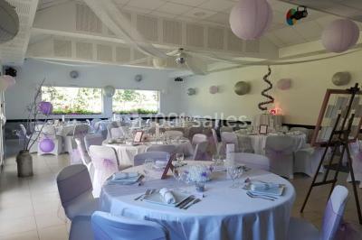 Paysage champêtre avec un étang entouré d'arbres, une barrière en bois au premier plan et un ciel dégagé.