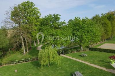 Paysage champêtre avec un étang entouré d'arbres, une barrière en bois au premier plan et un ciel dégagé.