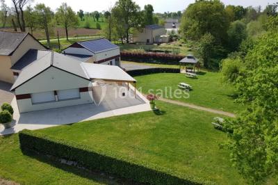 Paysage champêtre avec un étang entouré d'arbres, une barrière en bois au premier plan et un ciel dégagé.