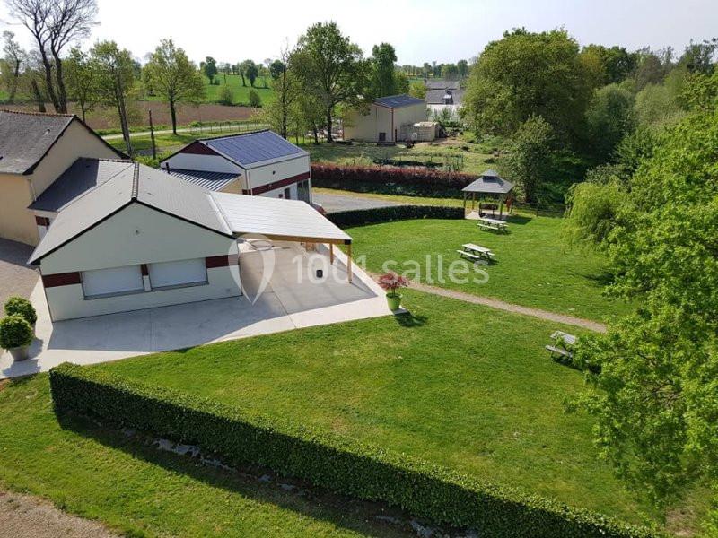 Vue aérienne d'un espace extérieur avec bâtiments, pelouse, tables de pique-nique et un kiosque entouré de verdure.