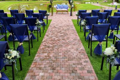 Paysage champêtre avec un étang entouré d'arbres, une barrière en bois au premier plan et un ciel dégagé.