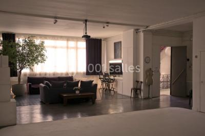 Espace intérieur lumineux avec un studio photo, canapé violet, table en bois et décoration moderne.