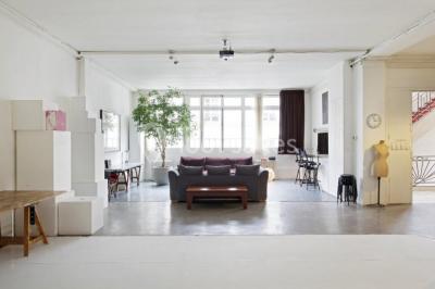 Espace intérieur lumineux avec un studio photo, canapé violet, table en bois et décoration moderne.