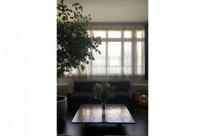 Espace intérieur lumineux avec un studio photo, canapé violet, table en bois et décoration moderne.