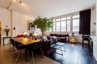 Espace intérieur lumineux avec un studio photo, canapé violet, table en bois et décoration moderne.