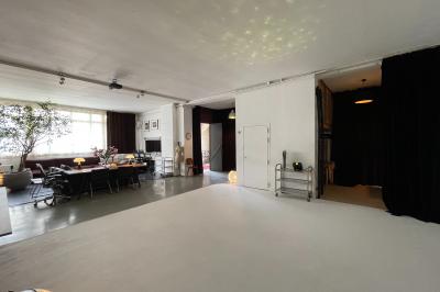 Espace intérieur lumineux avec un studio photo, canapé violet, table en bois et décoration moderne.