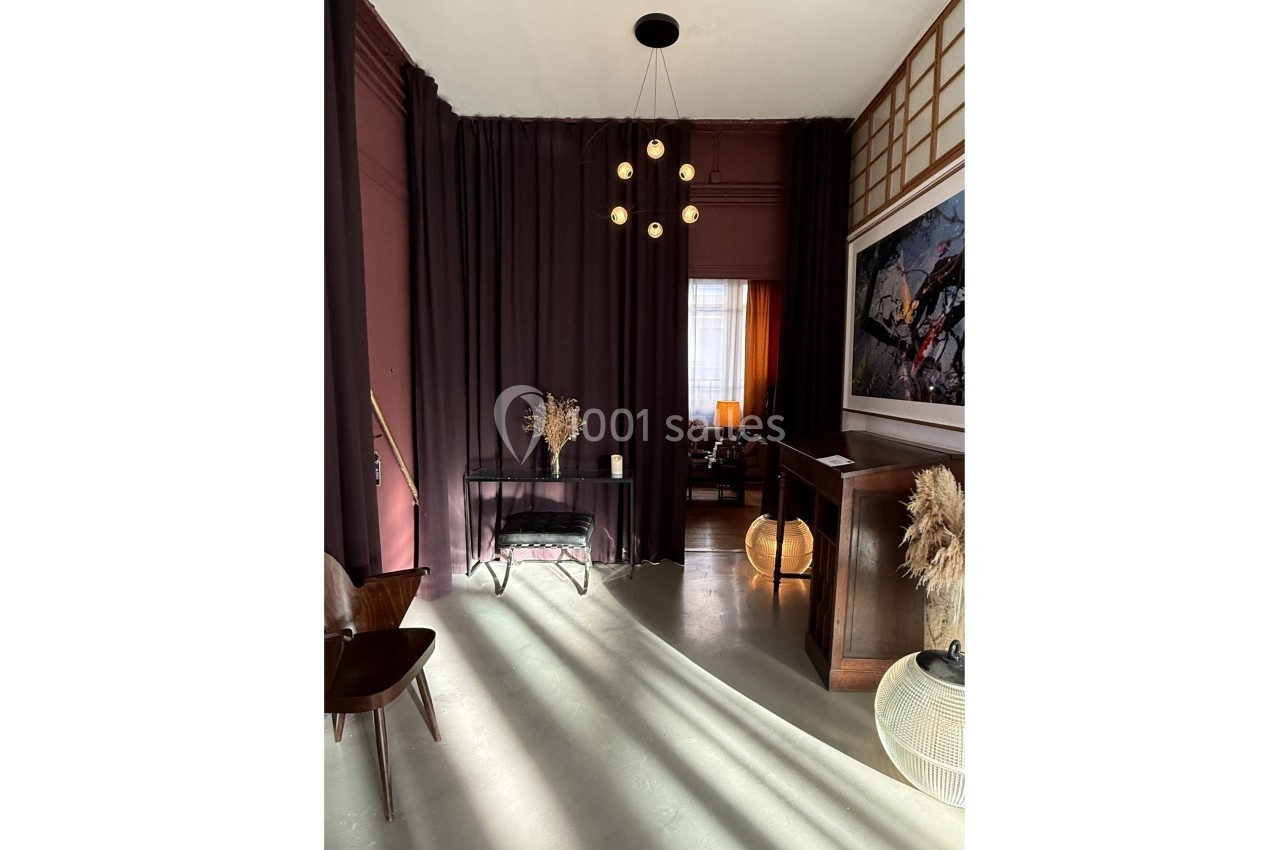 Espace intérieur élégant avec rideaux sombres, mobilier minimaliste, suspension lumineuse et décorations naturelles.