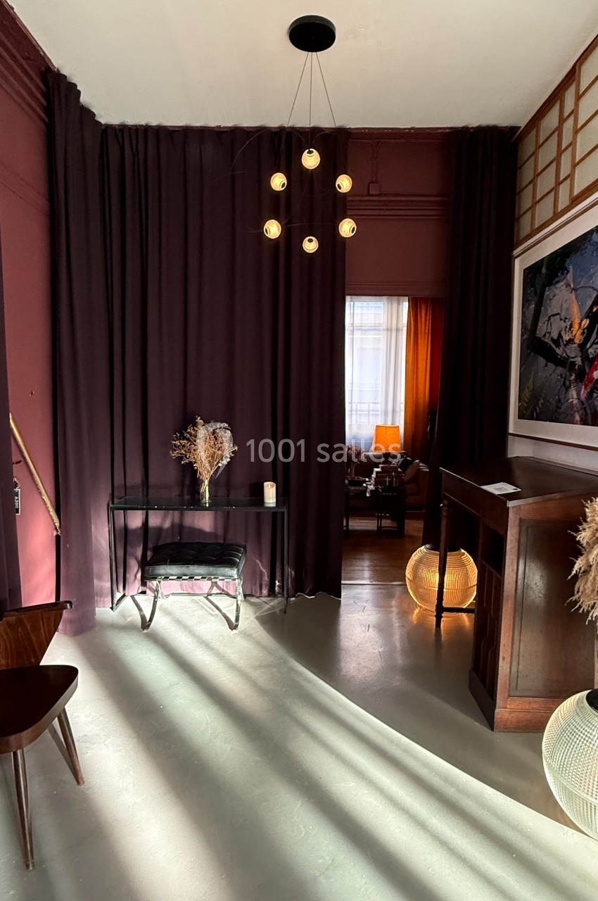 Entrée décorée avec des rideaux violets, mobilier en bois, éclairage tamisé et éléments de décoration naturels.