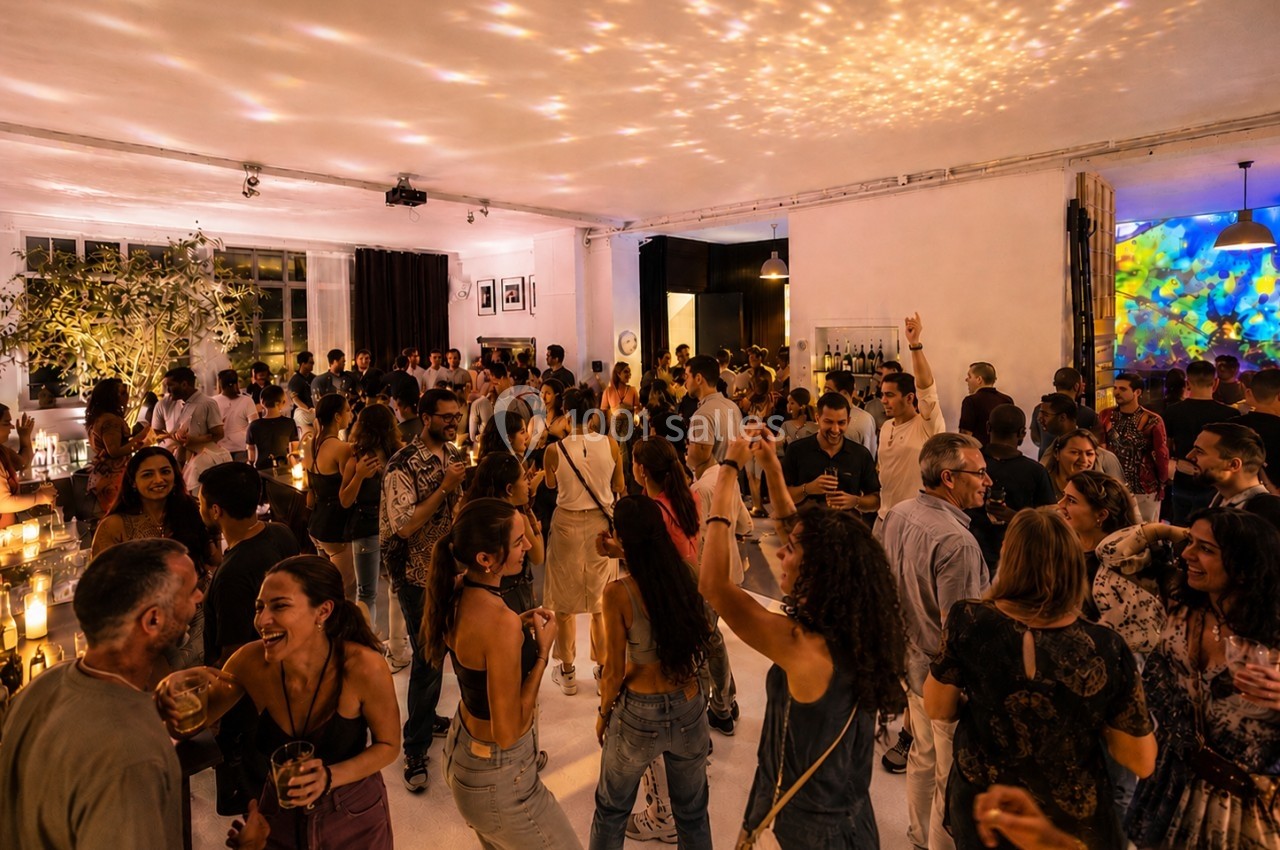 Groupe de personnes dans une salle animée, dansant et discutant sous des lumières tamisées et festives.