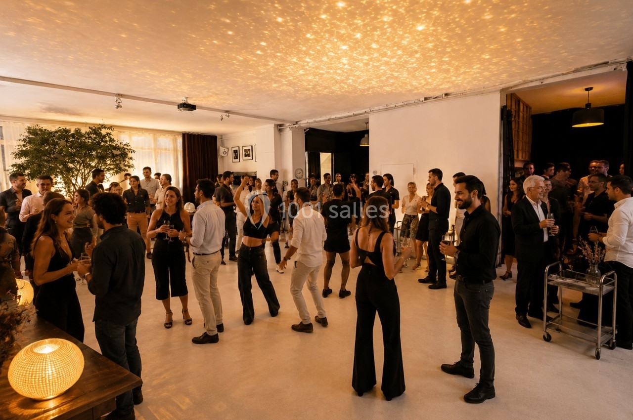 Groupe de personnes discutant et dansant dans une salle lumineuse avec un éclairage chaleureux et une ambiance conviviale.