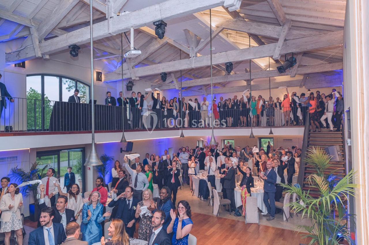 Salle de réception lumineuse avec des invités debout et assis, célébrant dans une ambiance festive.
