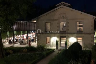 Un groupe de personnes joue au ballon sur une pelouse devant un grand bâtiment ancien sous un ciel dégagé.