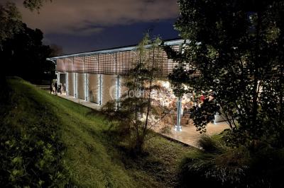 Un groupe de personnes joue au ballon sur une pelouse devant un grand bâtiment ancien sous un ciel dégagé.