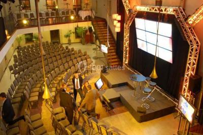 Un groupe de personnes joue au ballon sur une pelouse devant un grand bâtiment ancien sous un ciel dégagé.