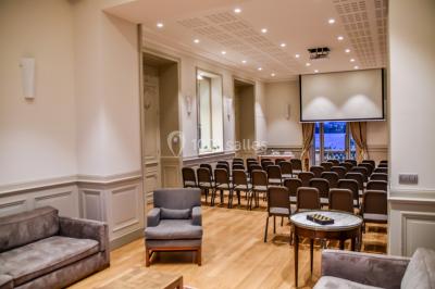 Un groupe de personnes joue au ballon sur une pelouse devant un grand bâtiment ancien sous un ciel dégagé.