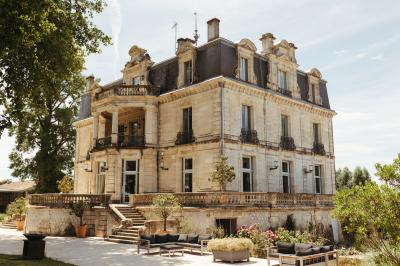 Un groupe de personnes joue au ballon sur une pelouse devant un grand bâtiment ancien sous un ciel dégagé.
