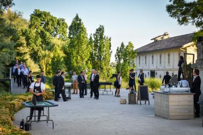 Un groupe de personnes joue au ballon sur une pelouse devant un grand bâtiment ancien sous un ciel dégagé.
