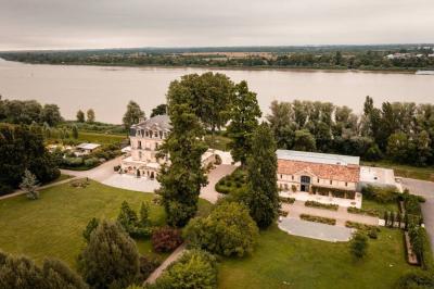 Un groupe de personnes joue au ballon sur une pelouse devant un grand bâtiment ancien sous un ciel dégagé.