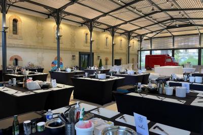 Un groupe de personnes joue au ballon sur une pelouse devant un grand bâtiment ancien sous un ciel dégagé.
