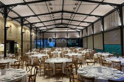 Un groupe de personnes joue au ballon sur une pelouse devant un grand bâtiment ancien sous un ciel dégagé.
