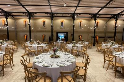 Un groupe de personnes joue au ballon sur une pelouse devant un grand bâtiment ancien sous un ciel dégagé.