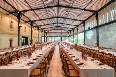 Un groupe de personnes joue au ballon sur une pelouse devant un grand bâtiment ancien sous un ciel dégagé.