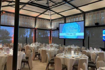 Un groupe de personnes joue au ballon sur une pelouse devant un grand bâtiment ancien sous un ciel dégagé.