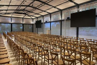Un groupe de personnes joue au ballon sur une pelouse devant un grand bâtiment ancien sous un ciel dégagé.