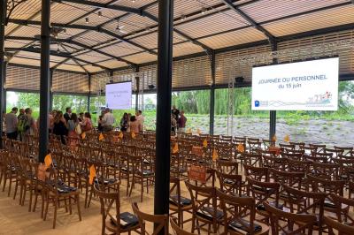 Un groupe de personnes joue au ballon sur une pelouse devant un grand bâtiment ancien sous un ciel dégagé.