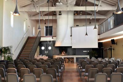 Un groupe de personnes joue au ballon sur une pelouse devant un grand bâtiment ancien sous un ciel dégagé.