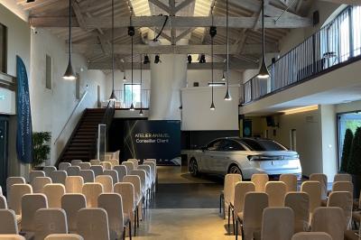 Un groupe de personnes joue au ballon sur une pelouse devant un grand bâtiment ancien sous un ciel dégagé.