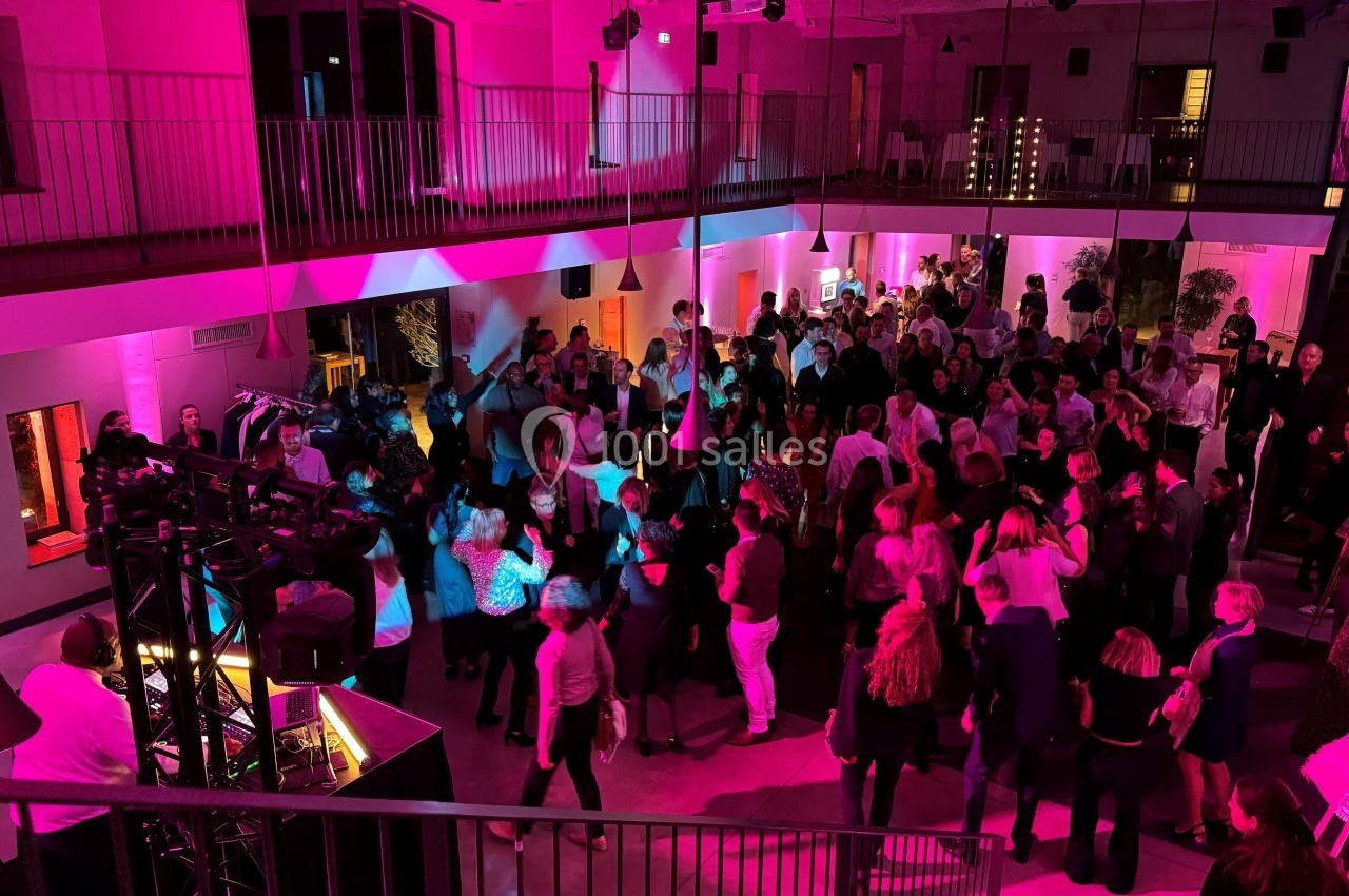 Groupe de personnes dans une salle éclairée par des lumières roses, rassemblées autour d'une piste de danse.