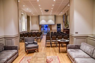 Un groupe de personnes joue au ballon sur une pelouse devant un grand bâtiment ancien sous un ciel dégagé.