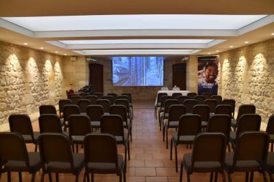 Un groupe de personnes joue au ballon sur une pelouse devant un grand bâtiment ancien sous un ciel dégagé.